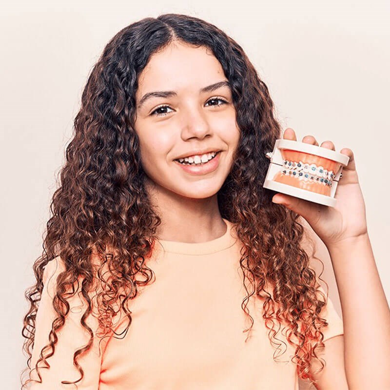 Teenager holding mouth diagram with braces